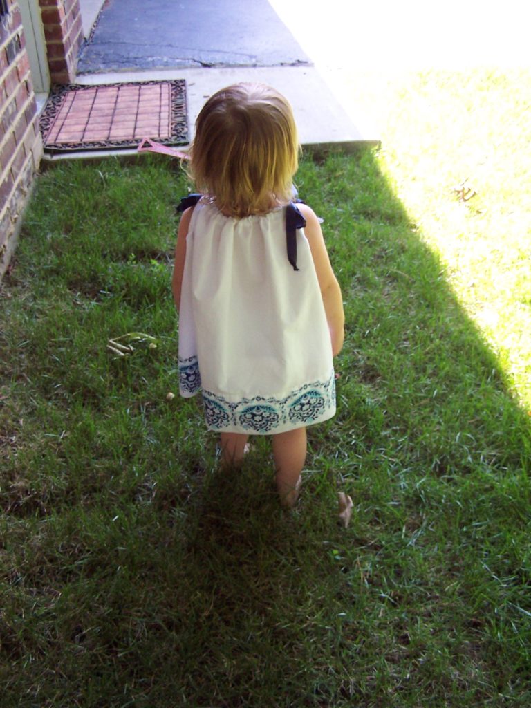 Toddler girl in a pillowcase dress looking away